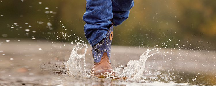 Close up of waterproof work boots stepping into a bubble of water.